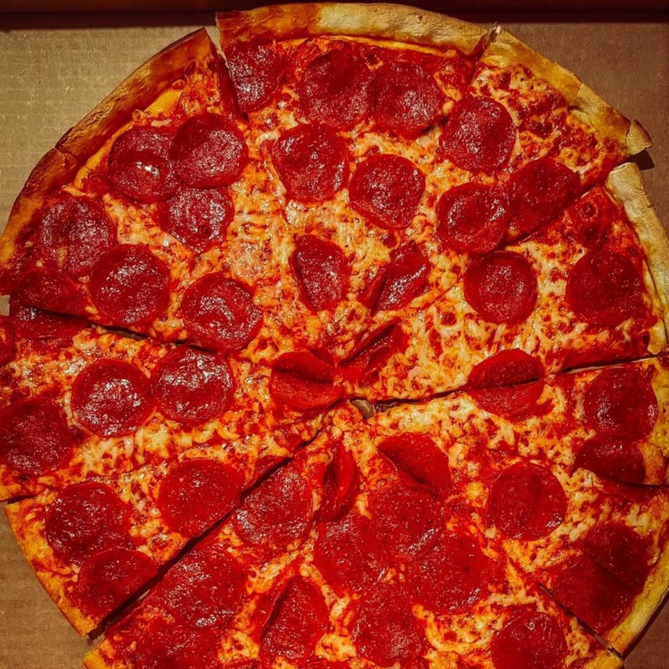 A whole pepperoni pizza from Fursty's Restaurant, sliced and ready to eat in a cardboard box.